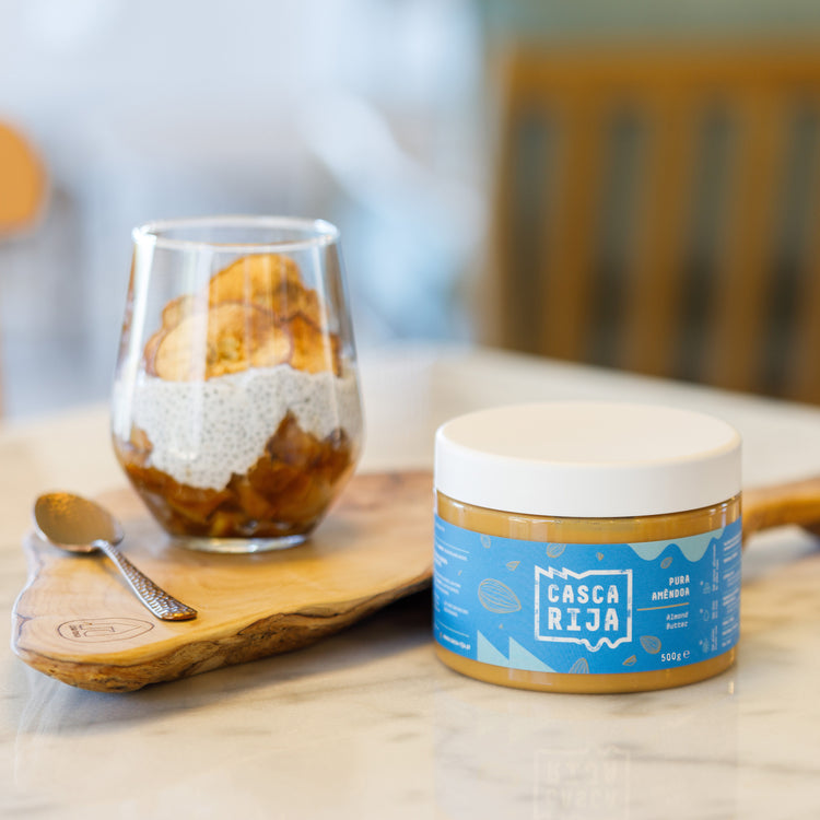 Casca Rija almond butter 500 g with almonds and a spoon on a wooden board