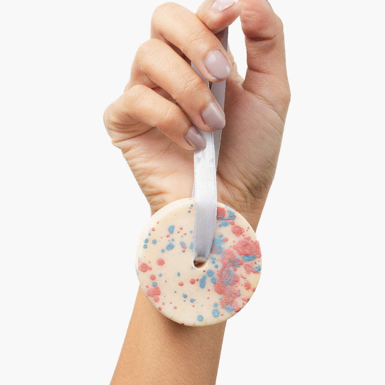 Mão segura fita cinzenta com disco sólido creme salpicado de azul e rosa
