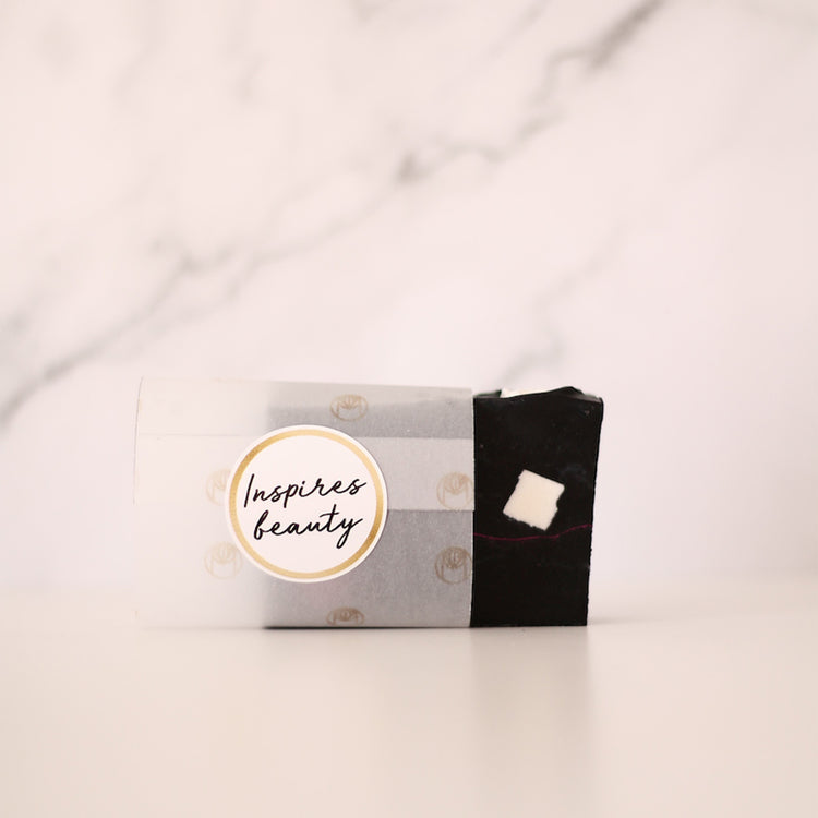 Barra preta de sabonete junto a caixa com selo Inspire beauty